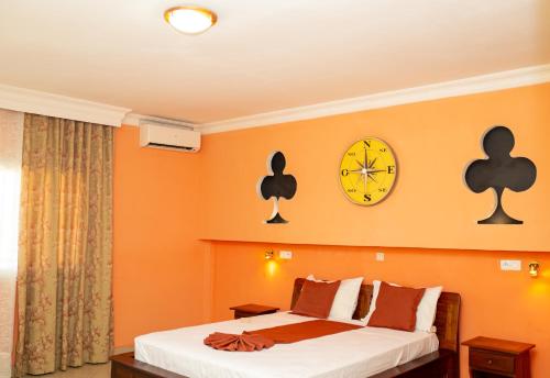 图利亚拉Amazone Hotel Tulear的卧室配有一张床,墙上挂着一个钟