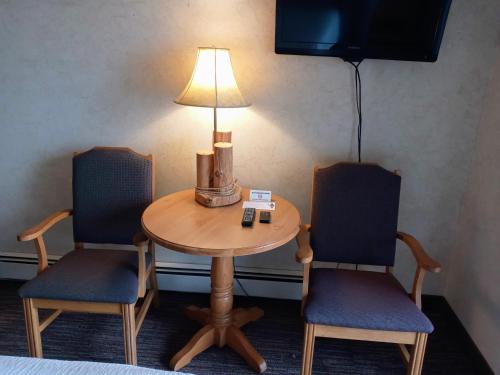 Tofte苏必利尔湖悬崖居民酒店的一张桌子,上面有两把椅子和一盏灯