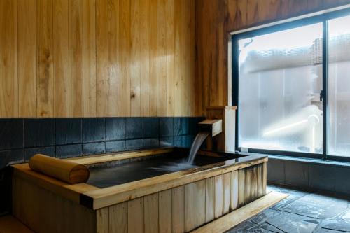 丰冈市森穗酒店的带窗户的客房内的热水浴池