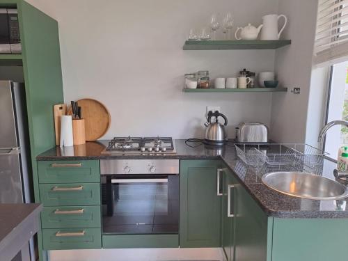 斯泰伦博斯Oak Village的厨房配有绿色橱柜、炉灶和水槽。