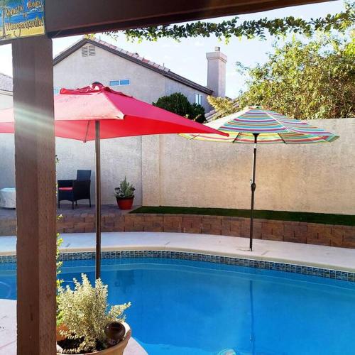拉斯维加斯New beautifully remodeled home in Las Vegas的两把遮阳伞坐在游泳池旁