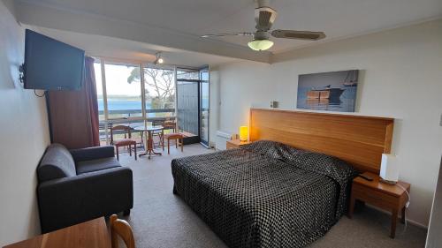 美洲河The River Suites, Kangaroo Island的一间卧室配有一张床、一把椅子和一张桌子