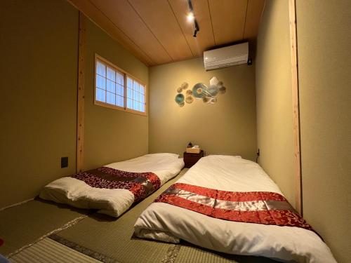 京都至の宿-京都南 Traditional Machiya Guesthouse的客房角落的两张床