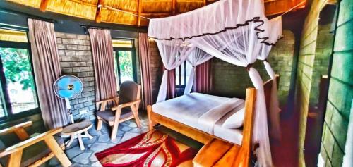 Pakwach EastGipir and Labongo Safari Lodge Ltd的一间卧室配有一张天蓬床和一把椅子