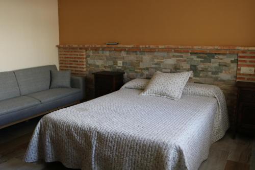 Los NavalucillosCasa Rural "La Cerecera"的一间卧室配有一张床和一张沙发