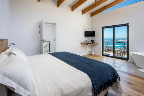 贝蒂湾OnTheRocksBB Solar Powered Guesthouse and Ocean Lodge的一间卧室配有一张床,浴室设有浴缸