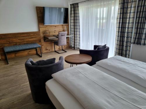 巴彻尔堡Hotel Beinbauer的酒店客房带两张床和一张桌子以及椅子。