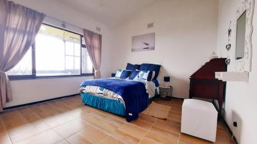 谢普斯敦港Alpero Umtentweni的一间卧室设有蓝色的床和窗户。