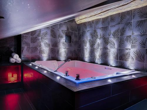 圣艾蒂安Suite Privative Rouge baiser - Spa & Jacuzzi - Love Room à Saint Etienne的浴室配有浴缸和红灯。