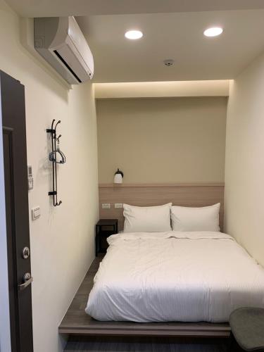 Ruifang晶晶輕旅民宿的一间卧室配有一张带白色床单的大床