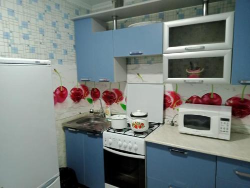 休钦斯克Квартиры的厨房配有炉灶、微波炉和红苹果