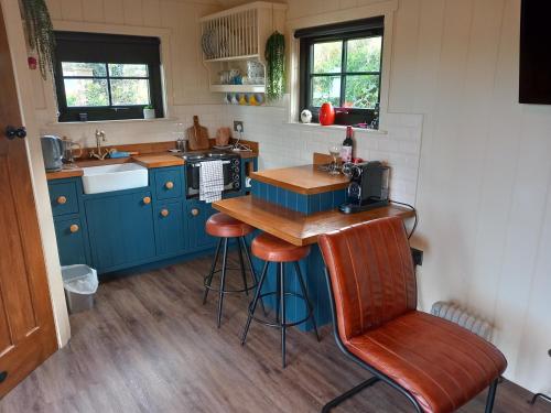韦斯特波特Delightful Shepherds Hut的厨房配有蓝色橱柜、柜台和凳子