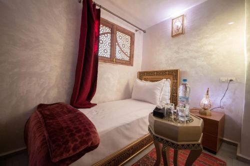 非斯Riad Fes Elite的一间卧室配有一张床、一张桌子和一个窗户。