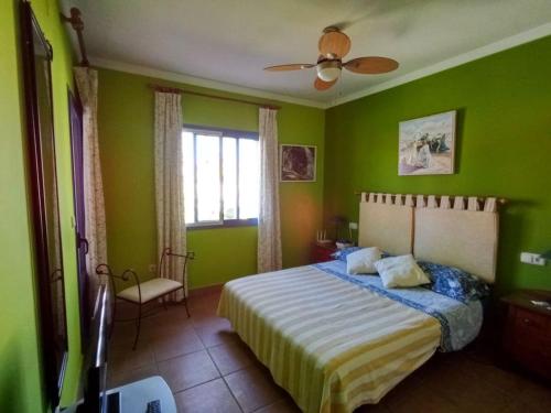 韦尔瓦Adosado playa Islantilla campo de golf的绿色卧室配有床和吊扇
