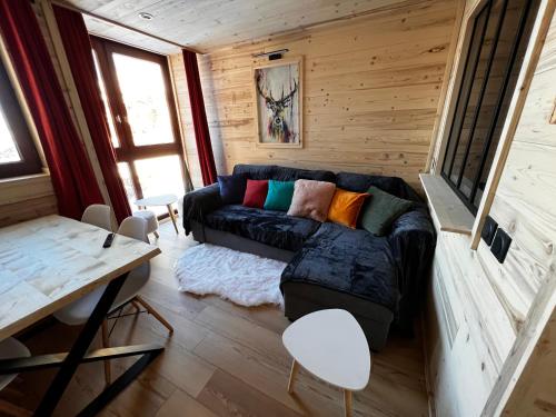 葱仁谷Les appartements Makalu Val Thorens的一间位于小房子内的客厅,客厅里配有黑色沙发