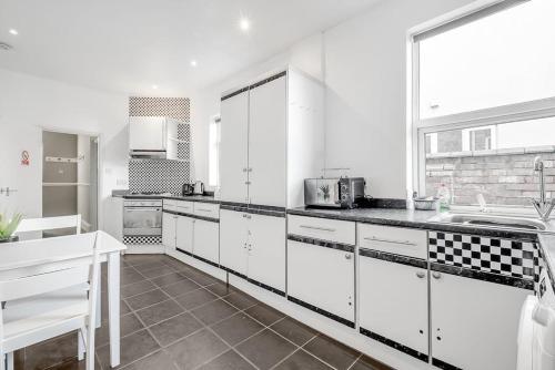 北安普敦Spacious Home - Ideal for Contractors的厨房配有白色橱柜和黑色台面