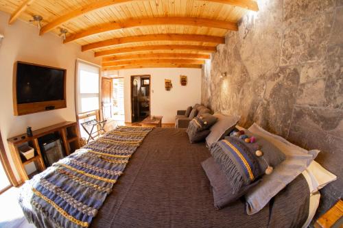 圣佩德罗·德·阿塔卡马Lodge Quelana的一张大床,位于一个石墙房间内