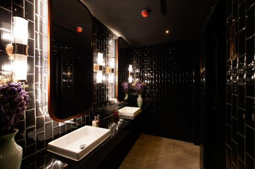 曼谷The Ember Hotel Khaosan的黑色浴室设有水槽和镜子
