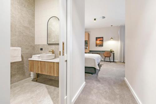 塔南达The Tanunda Club Guest Suites的一间带水槽的浴室和一张位于客房内的床