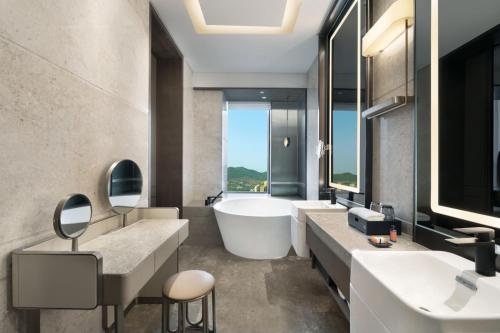 济南济南君瑞酒店的带浴缸、两个盥洗盆和浴缸的浴室。