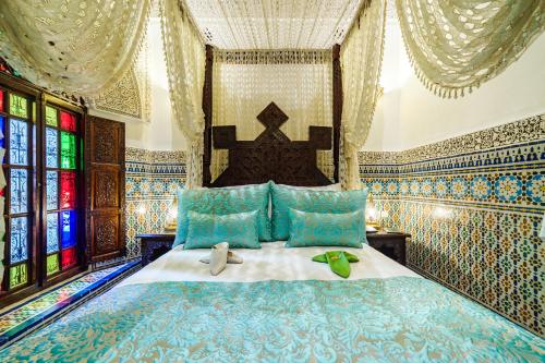 非斯Riad Rcif & Spa Originale的一间卧室配有一张带蓝色枕头的床和窗户。