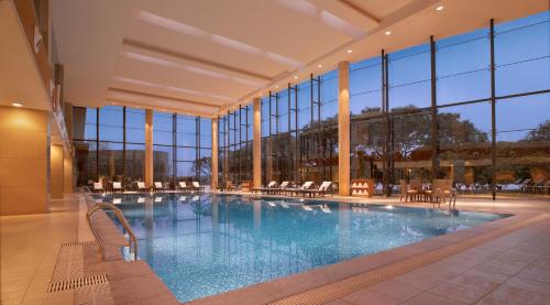 东莞东莞松山湖凯悦酒店的一座大型游泳池,位于一座带窗户的建筑内