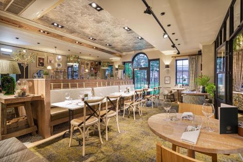 奥斯威斯The Wynnstay Hotel, Oswestry, Shropshire的餐厅设有木桌、椅子和窗户。