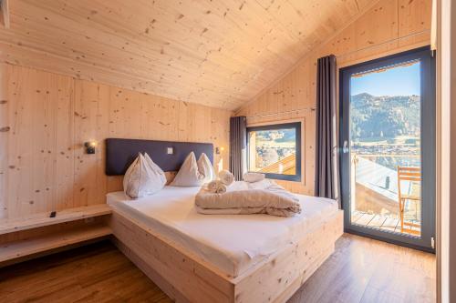 施泰纳赫布伦纳Bergeralm Chalets by ALPS RESORTS的木制客房的一张床铺,设有大窗户
