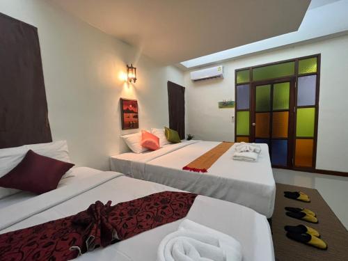 华欣Rainforest Huahin Village Hotel的酒店客房设有两张床和窗户。