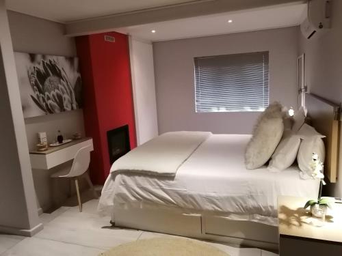 斯泰伦博斯Lauradale Accommodation的卧室配有白色的床和红色的墙壁