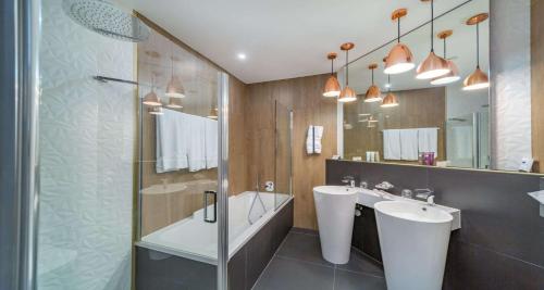 穆尔滕MIA SeePark Hotel Murten的浴室设有2个水槽、浴缸和镜子