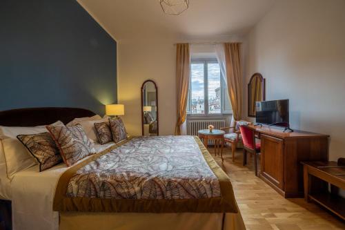 佛罗伦萨维拉尼酒店的一间卧室配有一张床、一张书桌和一台电视