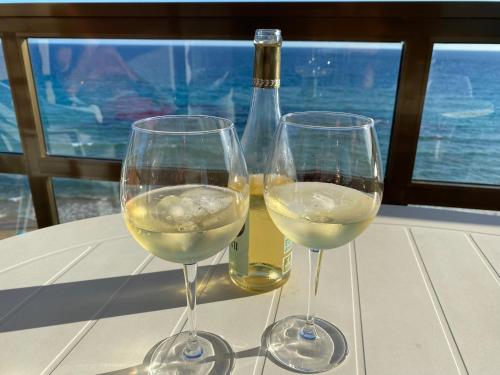 艾法奇Calpe Mar y Playa的两杯白葡萄酒,旁边是一瓶葡萄酒