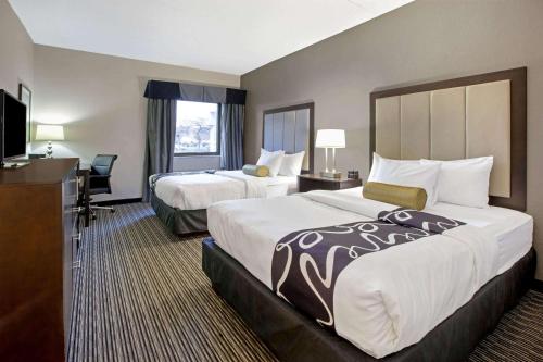 罗缪勒斯La Quinta Inn & Suites by Wyndham Detroit Metro Airport的酒店客房设有两张床和电视。