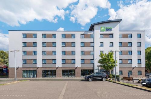 科隆Holiday Inn Express Cologne Mülheim, an IHG Hotel的一座白色的大建筑,停车场有停车位