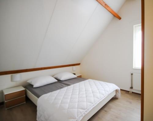 韦默尔丁厄Huisje 11 Wemeldinge的一间卧室配有白色床单