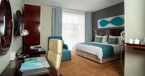 哈博罗内Tlotlo Hotel & Conference Centre的酒店客房设有一间带一张床和一张书桌的卧室