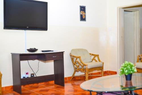 利隆圭Avon Garden Apartments Area 25的客厅配有书桌、椅子和电视