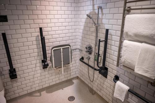 坎伯利Ely Hotel by Chef & Brewer Collection的带淋浴和毛巾的白色瓷砖浴室