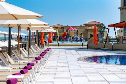 麦纳麦The Grove Resort Bahrain的一把带遮阳伞和游泳池的躺椅