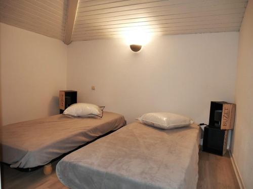 卡布勒通Villa Capbreton, 3 pièces, 4 personnes - FR-1-413-79的一间设有两张床的客房,墙上有一盏灯
