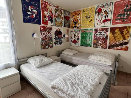 康博莱班Appartement Cambo-les-Bains, 3 pièces, 4 personnes - FR-1-495-20的墙上贴有海报的房间里设有两张床