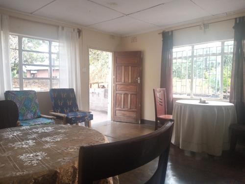 NamzungaBlue Waxbill Lodge的客厅配有桌椅和窗户。