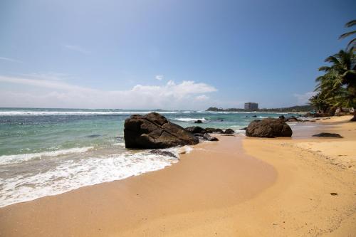 乌纳瓦图纳Happy Beach Villa Resort的一片拥有岩石和海洋的沙滩