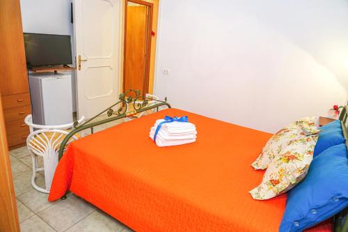切萨雷奥港B&B La Strea的一间卧室配有橙色床和毛巾