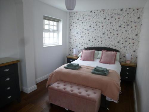 科尔温湾Delfryn Holiday Cottage的一间卧室配有带粉红色枕头的床和窗户。