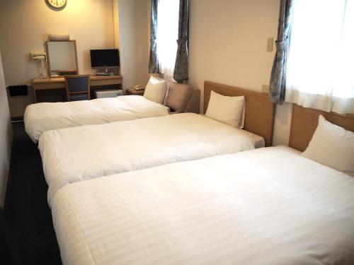 仙台绿色标志酒店的配有白色床单的酒店客房内的两张床