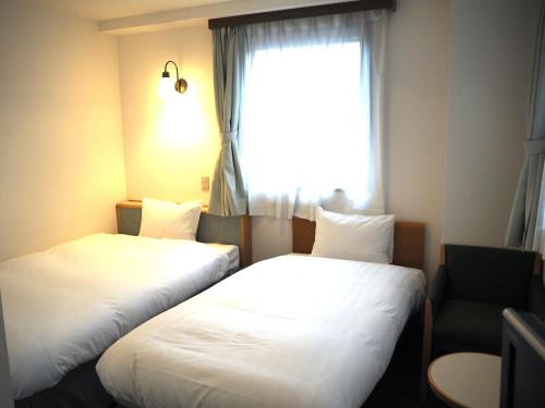 仙台绿色标志酒店的配有窗户的酒店客房内的两张床
