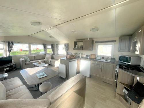 纽顿Trecco Bay Porthcawl Caravan 8 berth PALMS 4的厨房以及带沙发和桌子的客厅。