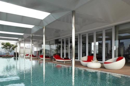 雅加达莫里西公寓式酒店的一座带红色和白色椅子的游泳池的建筑